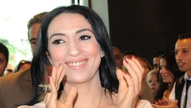 Salwa Idrissi Akhannouch smiling and clapping her hands during an event.