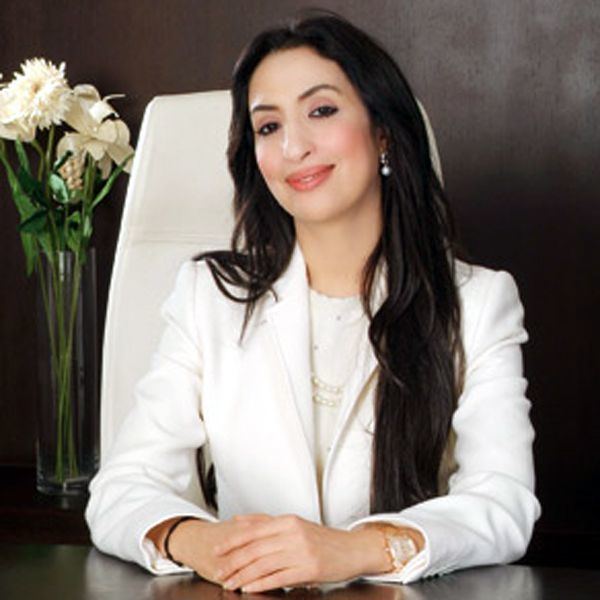 Salwa Idrissi Akhannouch smiling and sitting inside her office and wearing a white dress.