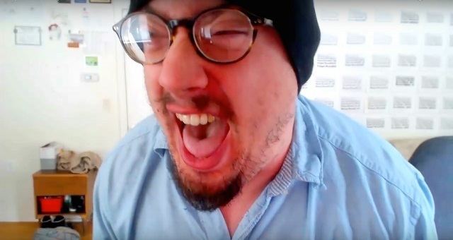 Sam Hyde shouting with an angry face, mustache, and beard while wearing a blue polo, eyeglasses, and black beanie