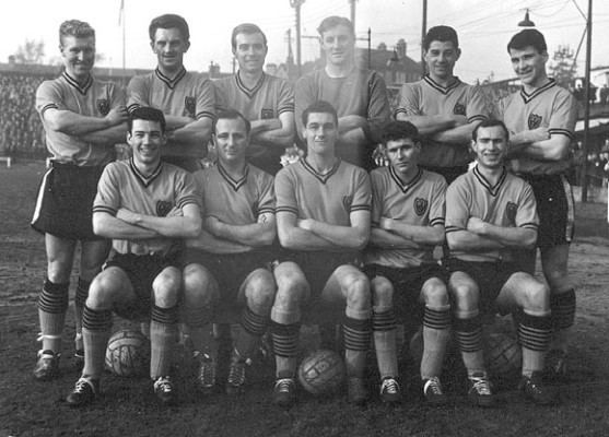 The Watford Football Club in the early 1960s. Back row left to right: Bobby Bell, George Catleugh, Vince McNiece, Jimmy Linton, Sammy Chung, Ken Nicholas. Front row left to right: Mike Benning, Dennis Uphill, Cliff Holton, Barry Hartle, Freddie Bunce. All are smiling with arms crossed over their chest and wearing a football jerseys.