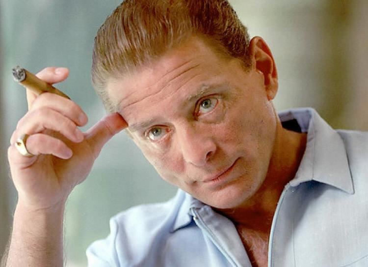Sammy Gravano looking at something and scratching his forehead while holding a cigarette.