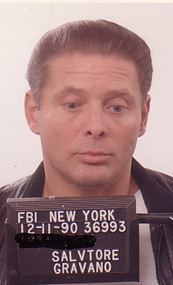 Sammy Gravano wearing a white shirt and a black leather jacket while posing for his mugshot.
