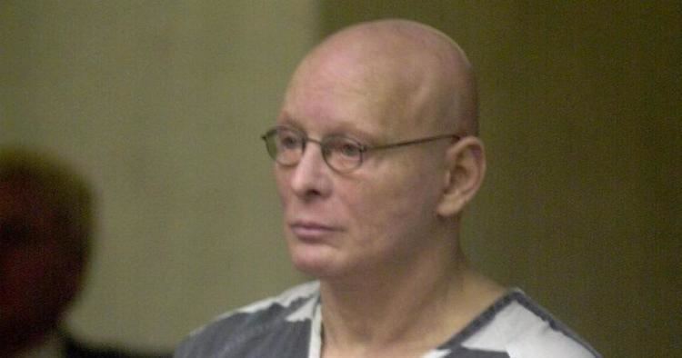 Sammy Gravano at a court session with his head shaved bald and wearing a white and gray shirt and eyeglasses.