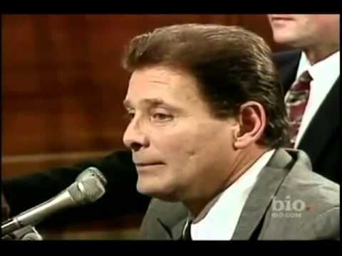 Sammy Gravano talking at a court session and wearing a gray suit and a white polo shirt.