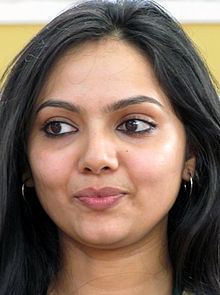 Samvrutha Sunil with a serious face, straight black hair, and wearing earrings.