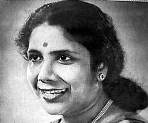 Sandhya Mukhopadhyay smiling while looking on the left side, with tied up hair and bindi on her forehead, and wearing a blouse and earrings