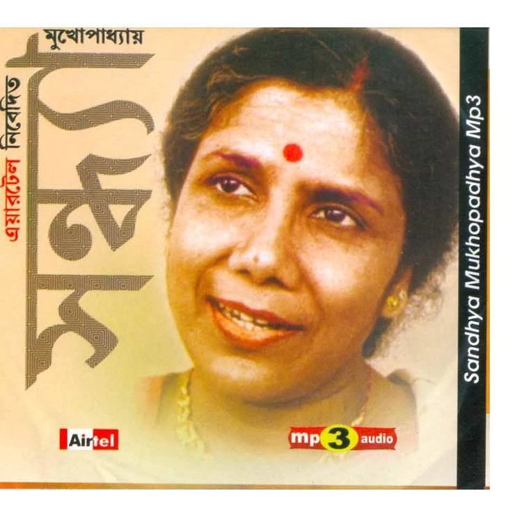 Mp3 audio cover featuring Sandhya Mukhopadhyay while smiling, with bindi on her forehead and wearing a blouse, gold necklace, and earrings