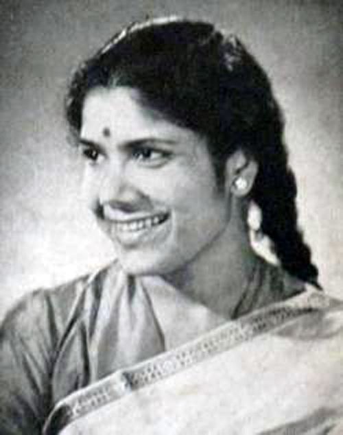 Sandhya Mukhopadhyay smiling while looking on the left side, with braided hair, and wearing a blouse, saree, and earrings