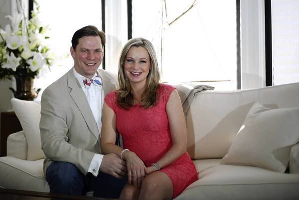 Sandra Smith wearing red-orange dress and John Conolly in his light brown coat, white long sleeves and bow tie while sitting on a couch