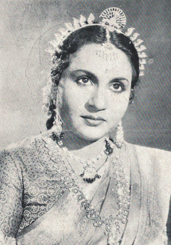 Santha Kumari wearing a headdress, necklace, earrings, and dress