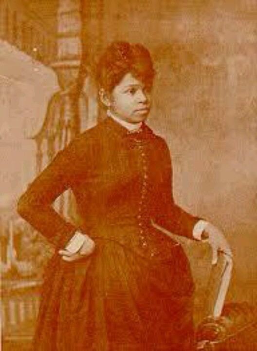 Sarah Boone is an African-American inventor who obtained the United States patent number 473,563 for her improvements to the ironing board. Sarah with a serious face while one hand is on her waist and the other one is holding a book, and wearing a black long sleeve dress over a white long sleeve top.