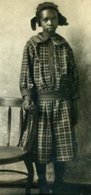 Sarah Rector standing and wearing a long sleeve with a chair beside her