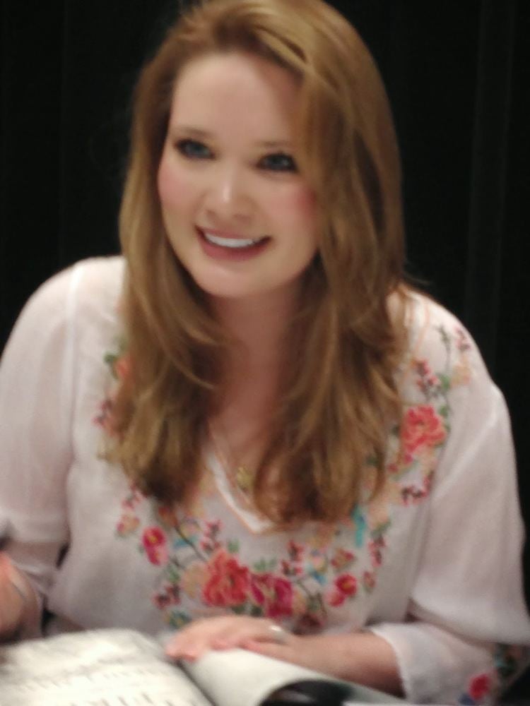 Sarah Rose Karr smiling, with blonde hair and wearing a floral blouse.