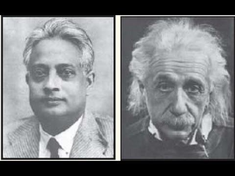 Satyendra Nath Bose on left is serious, has white hair, and wears white long sleeves, a black necktie under a gray lined suit.  Albert Einstein (right) is serious, has white hair and a mustache, he is wearing a white top under a black jacket.