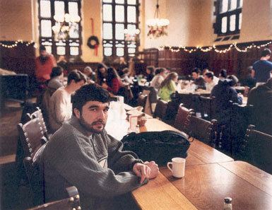 Sayed Rahmatullah Hashemi sitting on the chair in a dining hall while wearing gray long sleeves