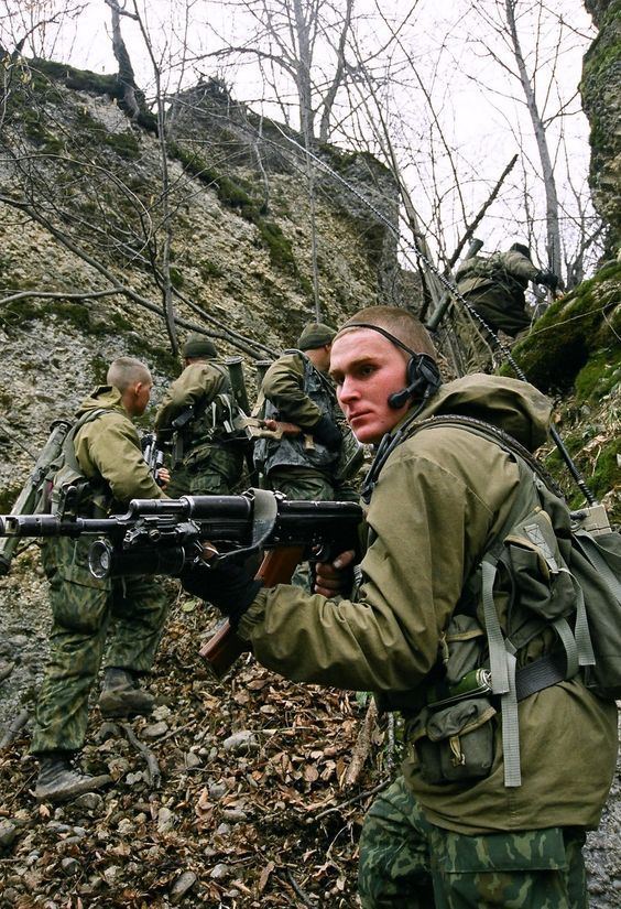 Group of soldiers holding their guns while climbing the mountain during the Second Chechen War