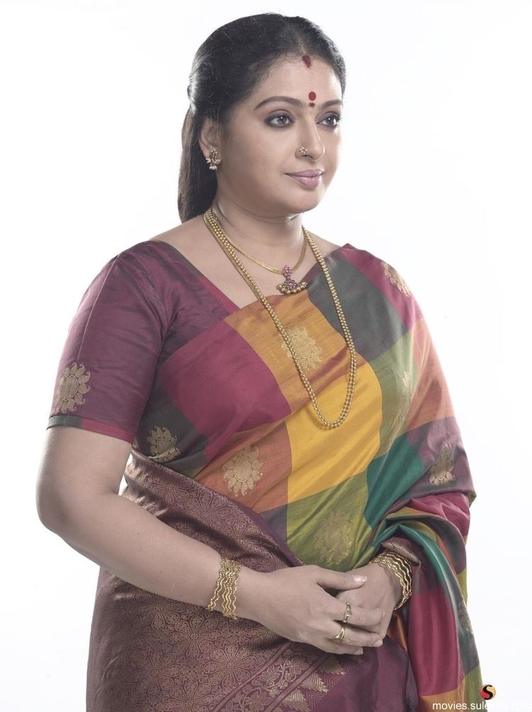 Seetha wearing earrings, a gold necklace, bangles, rings, and a Sari dress.