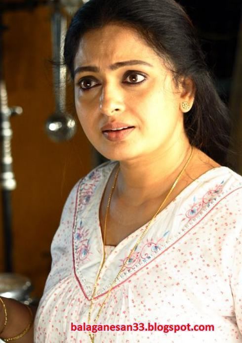 Seetha with black hair, wearing a gold necklace and a white shirt.