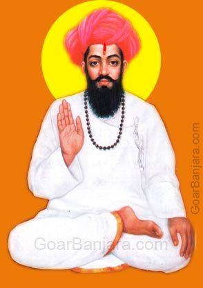Poster of Sevalal sitting cross-legged, wearing a brown necklace, red turban, and a white robe.