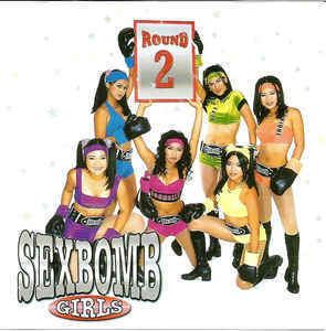 SexBomb Girls holding a boxing round card while wearing a colorful outfit