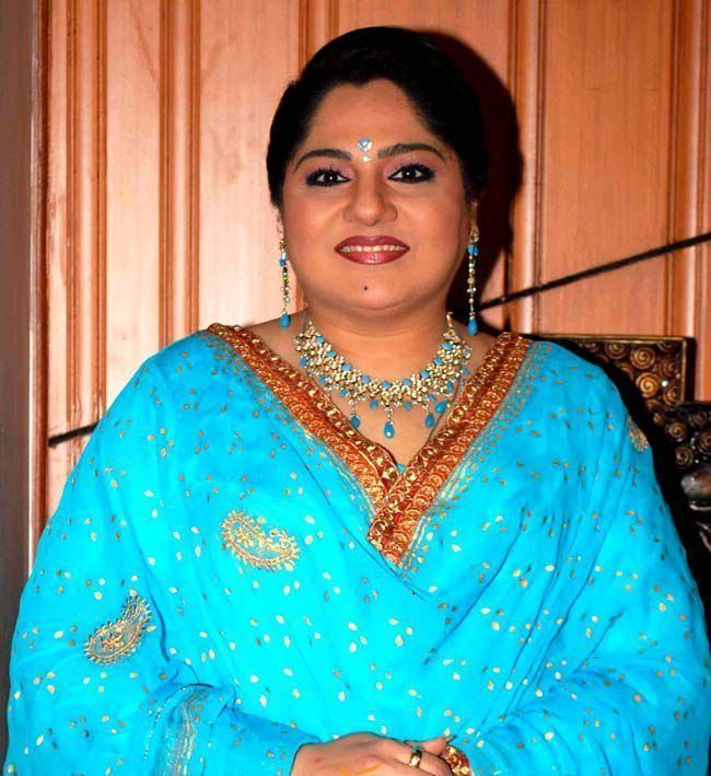 Shagufta Ali smiling, wearing earrings, a necklace, and a blue dress.