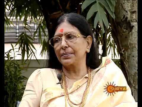 Sharada wearing eyeglasses, yellow dress and gold jewelries in one of her interviews