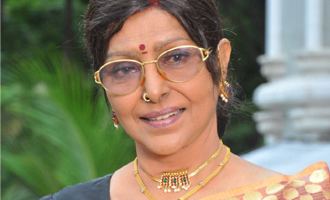 Sharada wearing eyeglasses, nose-jewel, earrings and gold necklace