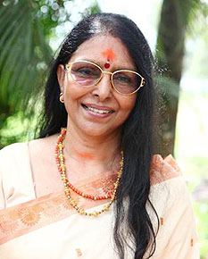 Sharada wearing cream and orange dress, eyeglasses and jewelries