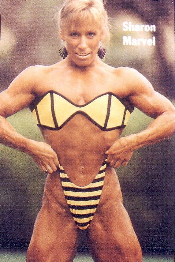 Sharon Marvel smiling while wearing a striped black and yellow bikini and earrings