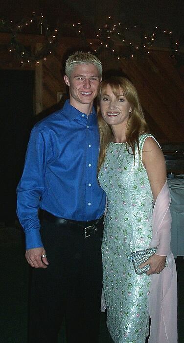 Shawn Toovey smiling and wearing blue long sleeves and black pants while the woman beside him wearing a blue-green dress