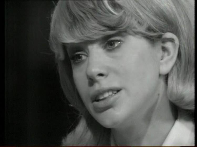 Sheila Fearn with a sad face, talking to someone teary-eyed, with short blonde hair and bangs, playing the role of Detective Sergeant Sarah Gifford in the 1969 TV series, "The Children of Delight". She is wearing a collared blouse.