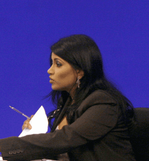 Shelly Dass holding a pen and a paper wearing a black long-sleeve shirt
