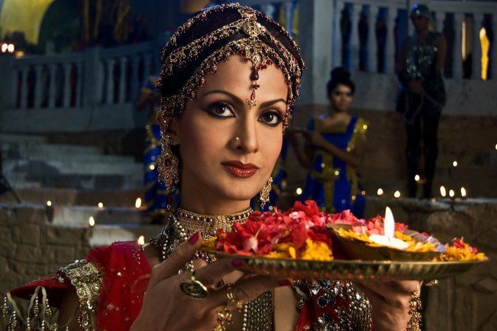 Shikha Swaroop smiling and showing a plate with a candle while wearing a glamorous traditional dress
