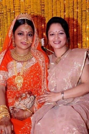 Shila Ahmed wearing traditional Indian clothing for women, earrings, necklace, and bracelets with a woman beside her also wearing traditional Indian clothing for women, earrings, necklace, and watch.