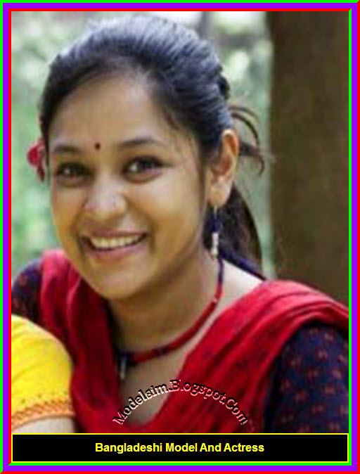 Shila Ahmed wearing earrings, a necklace, and a red and blue shirt.