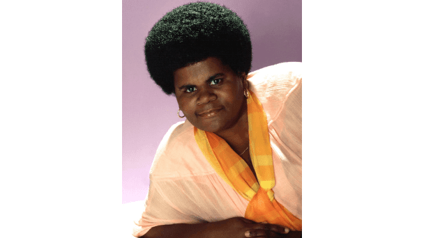Shirley Hemphill wearing earrings, a necklace, a yellow scarf, and a light pink shirt.