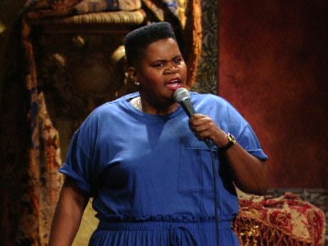 Shirley Hemphill wearing earrings, a watch, and a blue dress while holding a microphone.