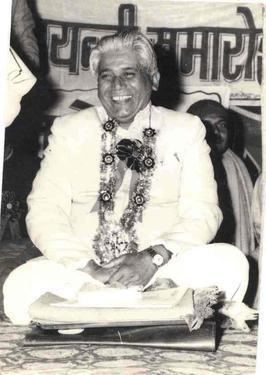 Shivmangal Singh Suman wearing white long sleeves, pants and rosette lei while laughing
