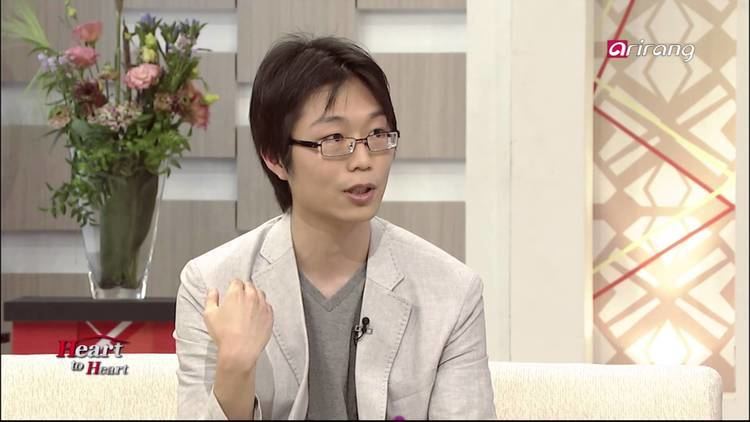 Sho Yano wearing eyeglasses, beige coat and gray inner shirt in his interview at Heart to Heart