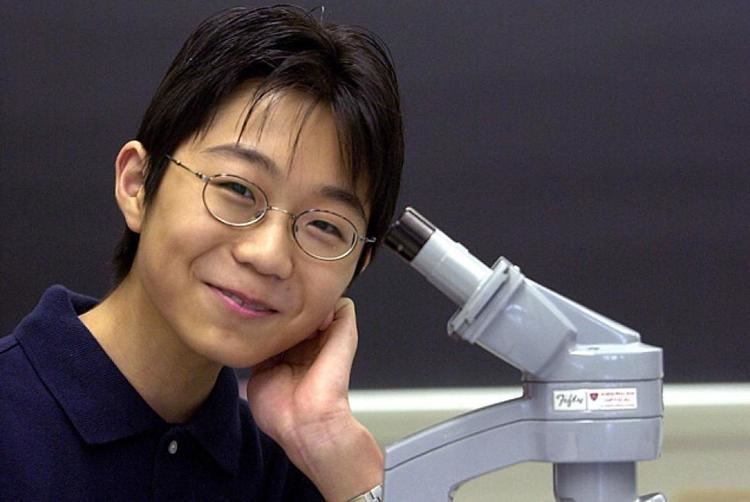 Young Sho Yano wearing eyeglasses and dark blue polo shirt while smiling