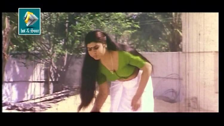 Anusha wearing a green shirt and a white skirt in a scene from the movie Shobhanam, 1997.