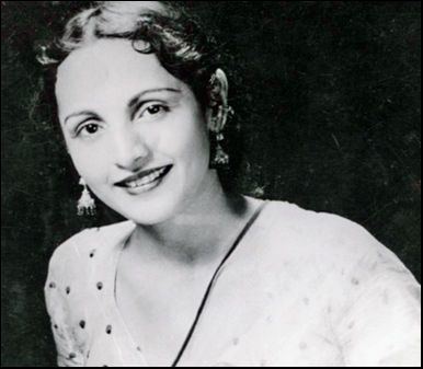 Shobhna Samarth smiles while wearing a white shirt and pair of earrings