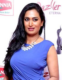 Shwetha Srivatsav with a tight-lipped smile while looking at something and wearing a blue sleeveless blouse and necklace