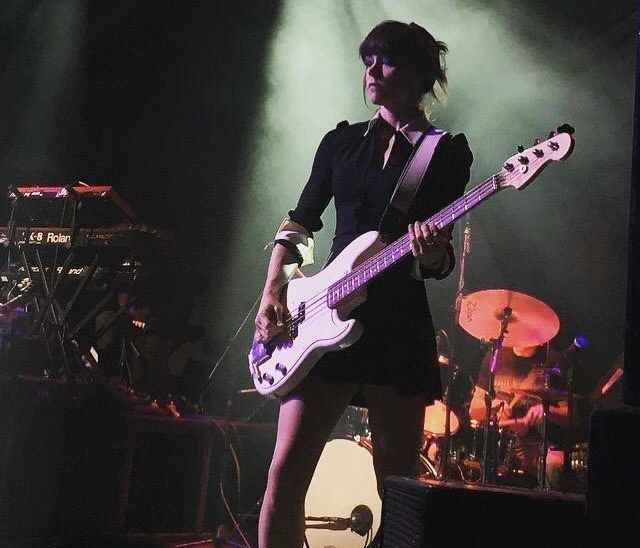Simone Butler playing the guitar while wearing a black dress