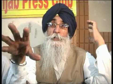 Simranjit Singh speaking having a beard and a mustache, wearing a white long sleeve under a brown vest, bracelet, eyeglasses, and black turban