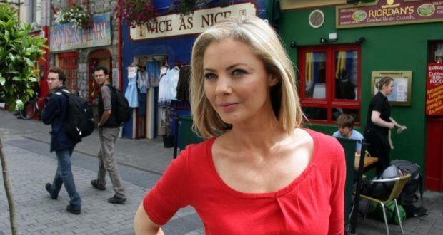 Siún Nic Gearailt with short blonde hair and wearing a red shirt while on the street.