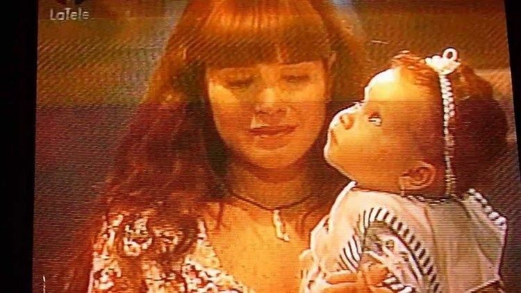Astrid Gruber as Sirena Baltazar holding a baby in a scene from Sirena (a 1993 Venezuelan telenovela).