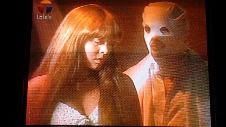 Astrid Gruber as Sirena Baltazar with a man wearing a white mask in a scene from Sirena (a 1993 Venezuelan telenovela).