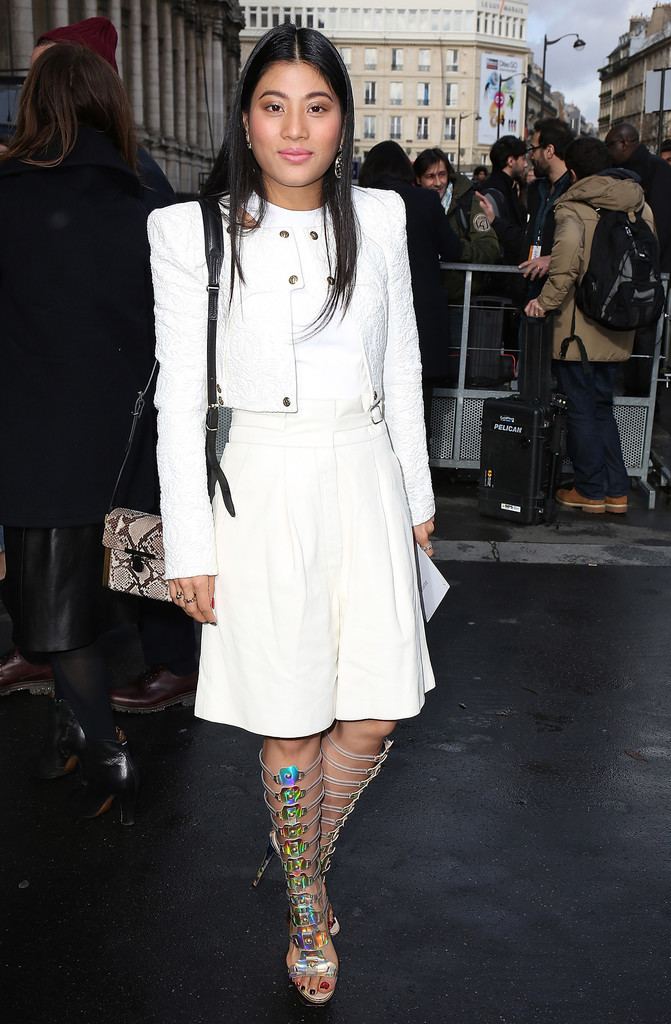 Sirivannavari Nariratana smiling while wearing a white blazer, white inner blouse, white skirt, and high heels paired with a snakeskin bag