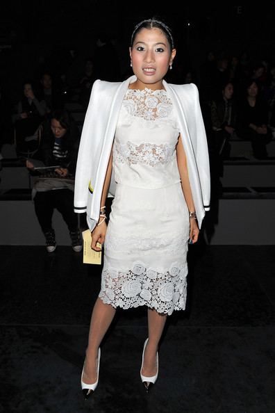 Sirivannavari Nariratana smiling while wearing a white coat, lace white dress, white heels, and some pieces of jewelry